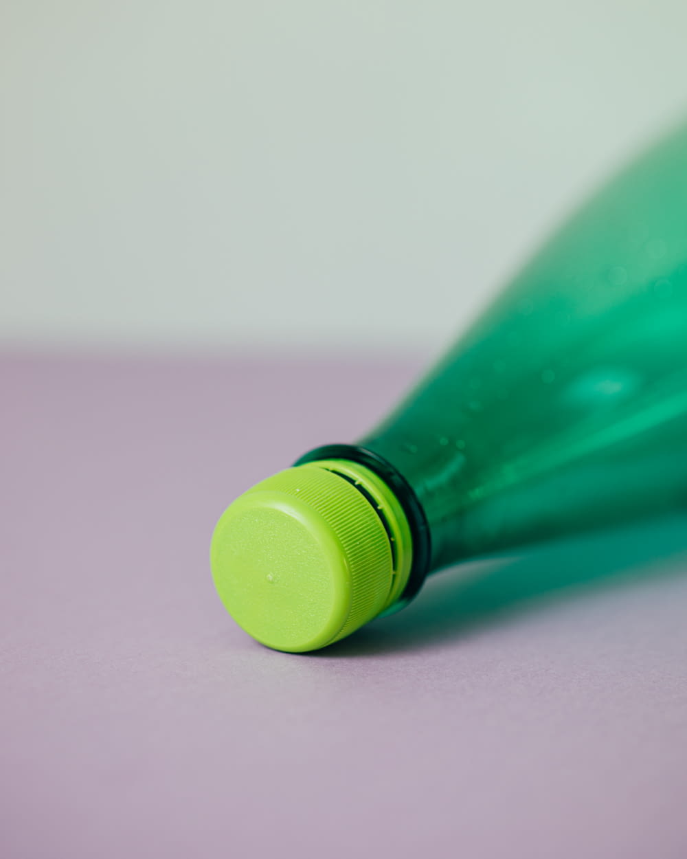 garrafa plástica verde na superfície rosa
