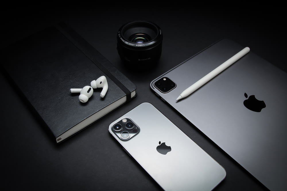 silver macbook beside black camera lens and black camera lens