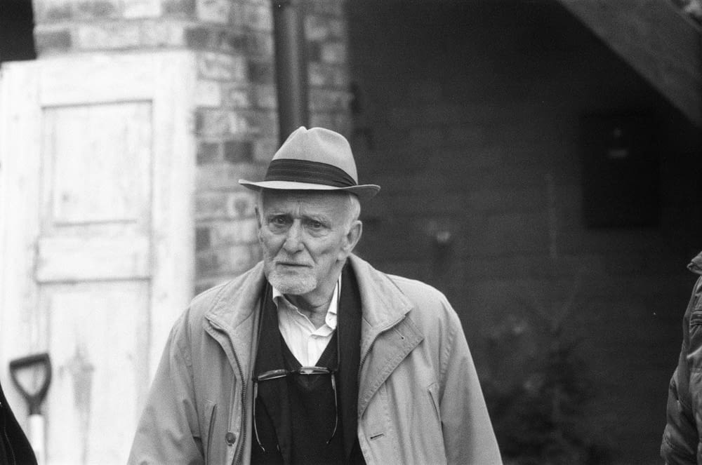 grayscale photo of man wearing hat and coat