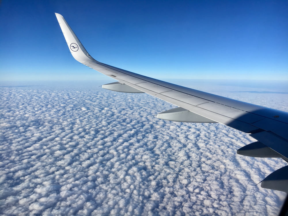 white airplane wing on white clouds during daytime
