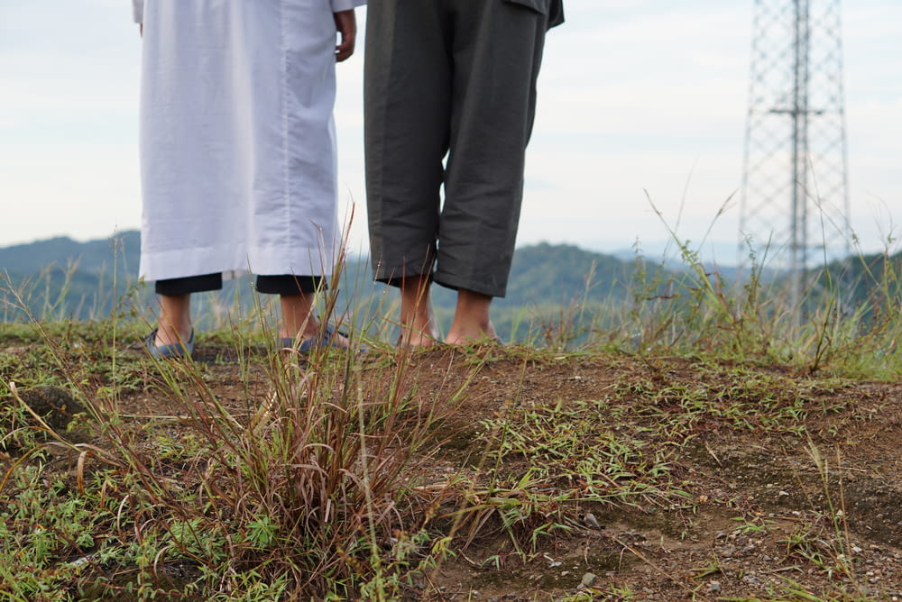 man and woman holding hands while walking on green grass field during daytime