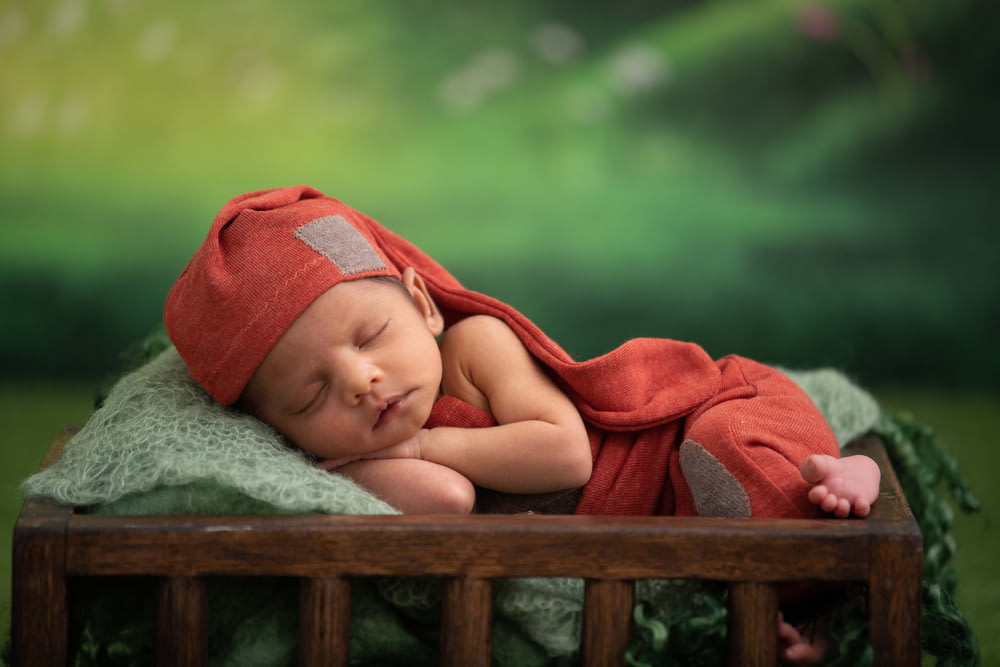 bébé en couverture rouge couché sur textile vert