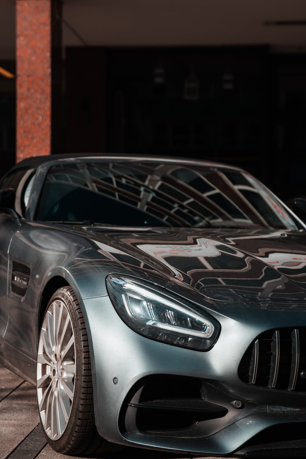 Mercedes Benz coupé argentée garée près d’un bâtiment en béton brun pendant la journée