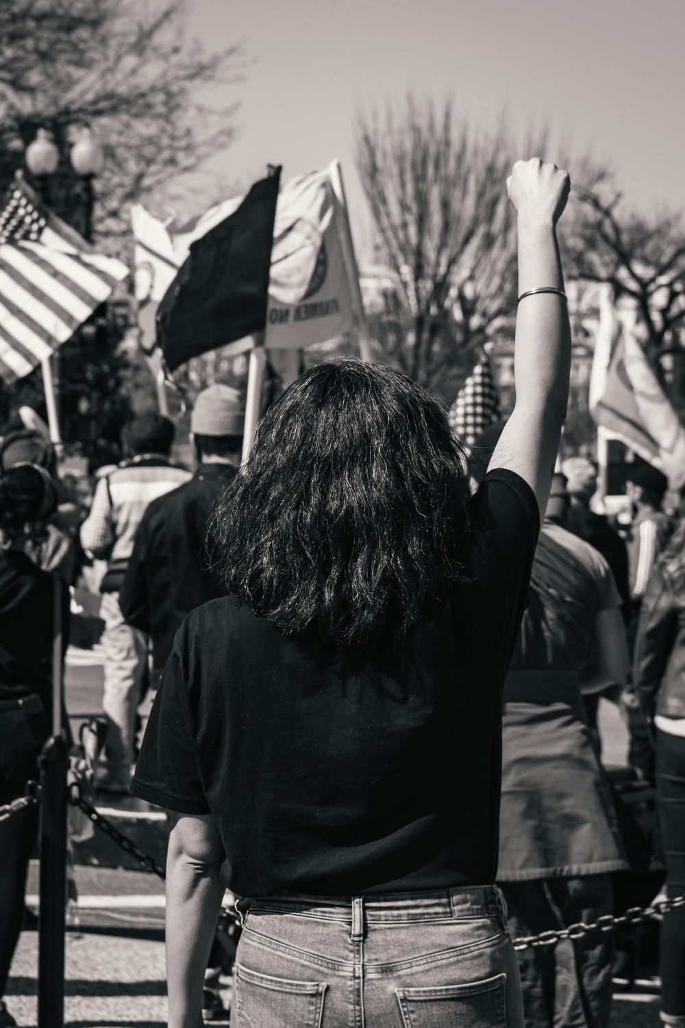 Foto en escala de grises de una mujer con camisa negra sosteniendo una bandera