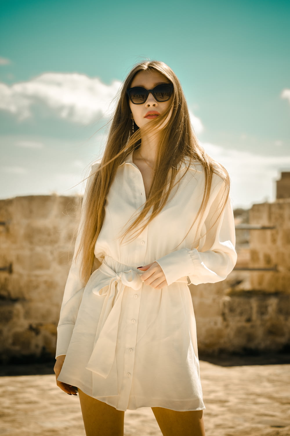 Frau im weißen langärmeligen Kleid mit schwarzer Sonnenbrille