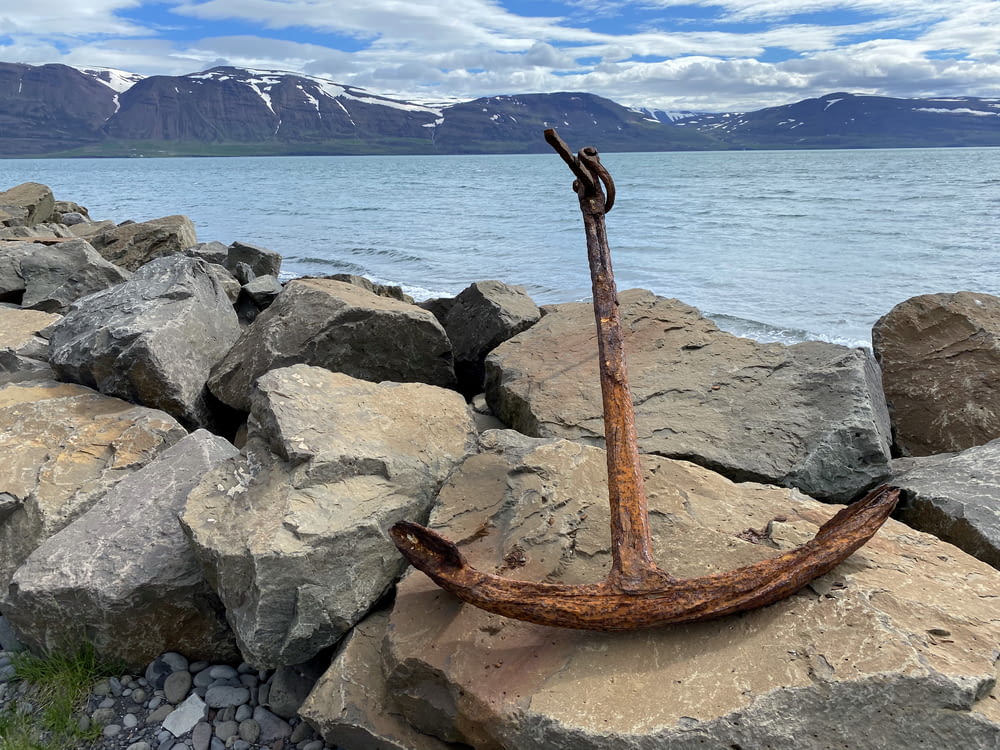 brown metal wheel on rocky shore during daytime
