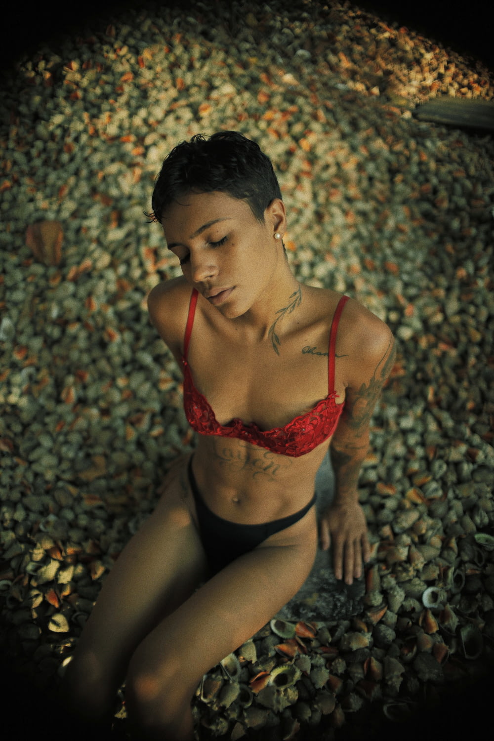 woman in red brassiere and black panty sitting on ground