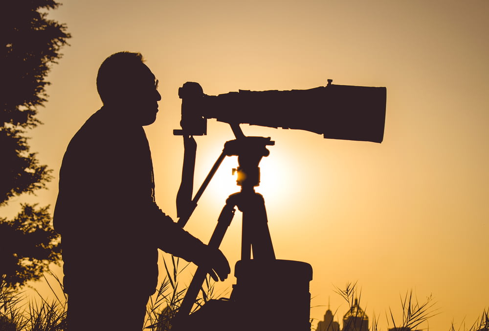 Silhouette d’un homme tenant une caméra au coucher du soleil
