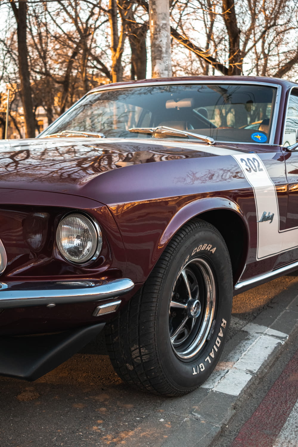 a maroon mustang mustang sitting on the side of the road
