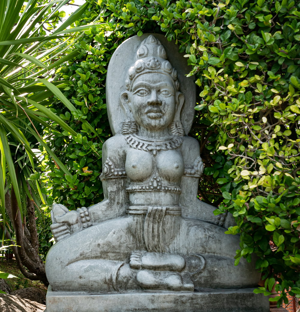 gray concrete statue surrounded by green plants