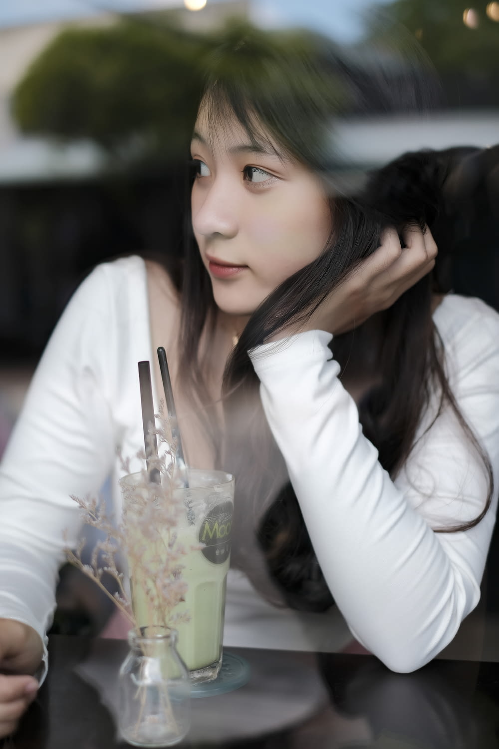 Frau in weißem Langarmhemd mit klarem Trinkglas
