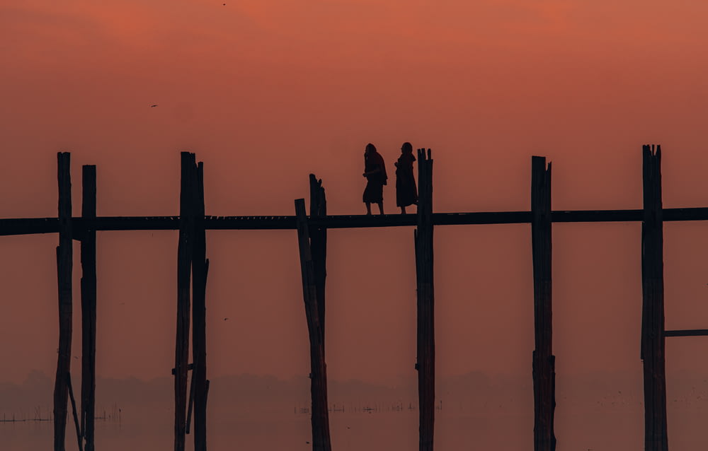 silhouette of people on wooden fence during sunset