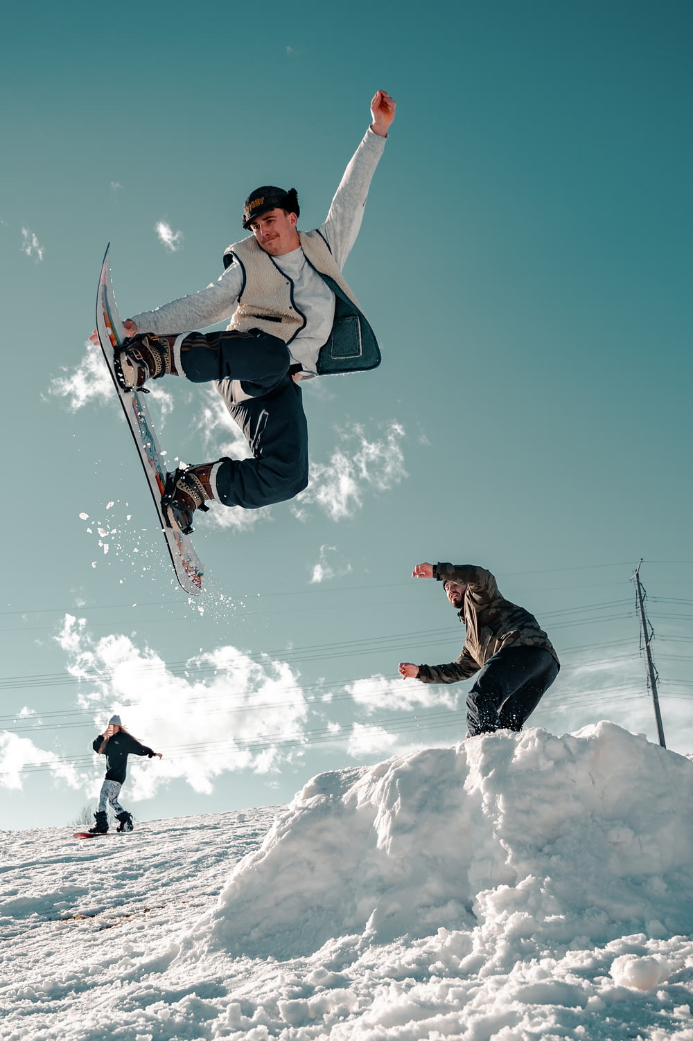 Mann in schwarzer Jacke und blauer Jeans fährt tagsüber Snowboard
