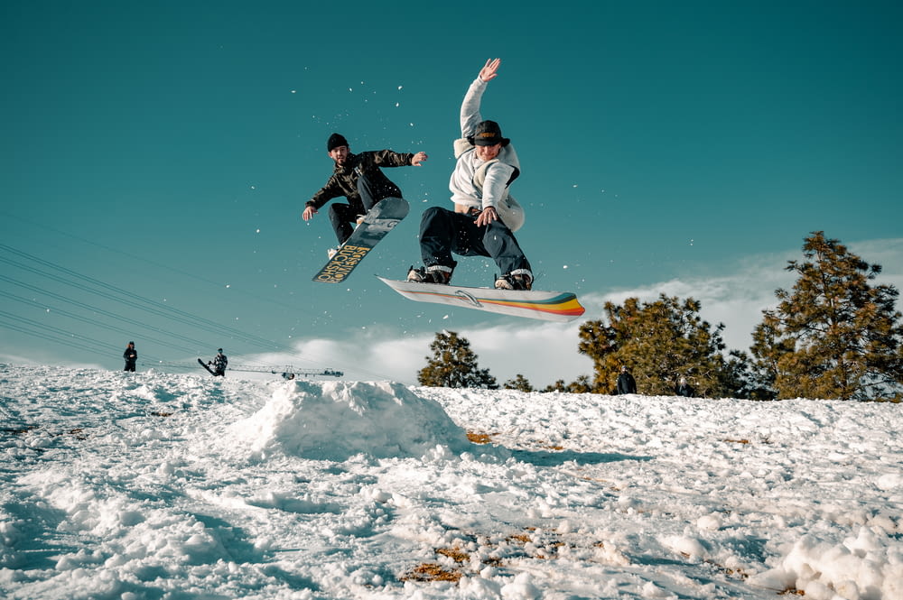 homem em jaqueta preta e branca andando no snowboard durante o dia