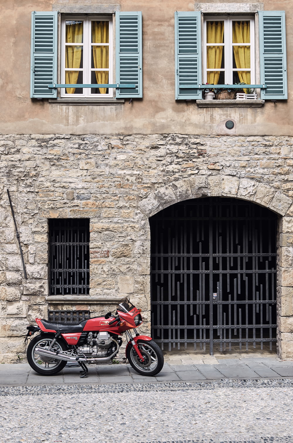 red and black motorcycle parked beside brown brick building