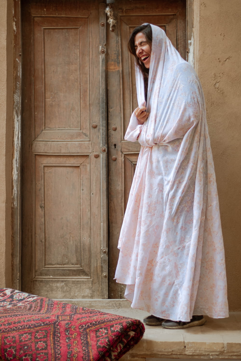 woman in white robe standing near brown wooden door