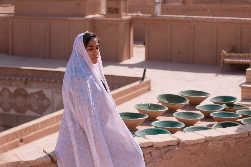 woman in white hijab standing near green round plastic basin