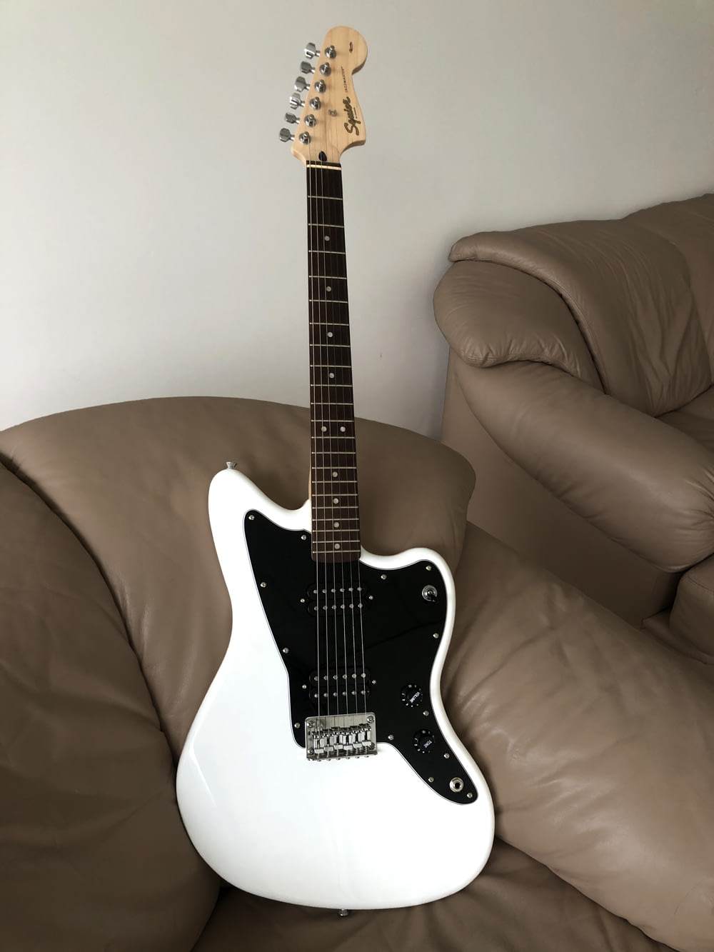 black and white stratocaster electric guitar on brown sofa