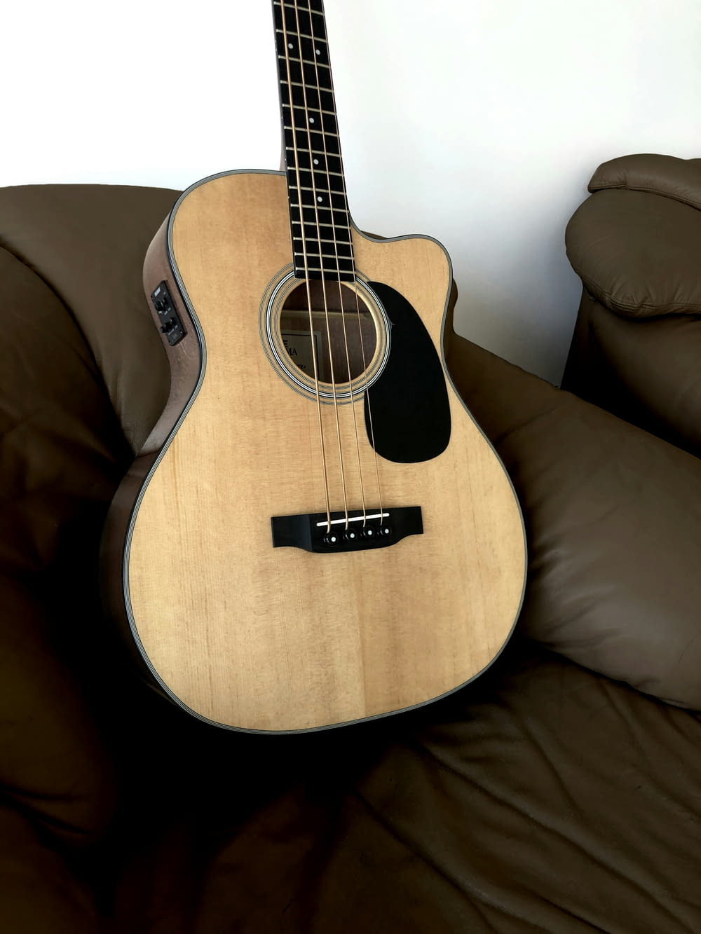 brown acoustic guitar on brown sofa