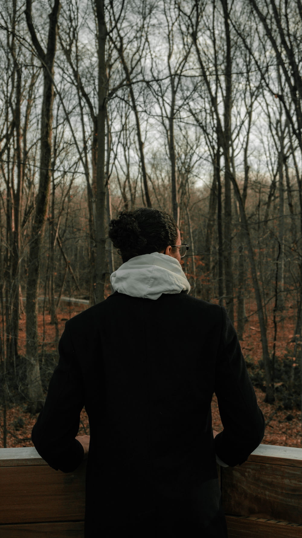 homme en veste noire debout dans les bois