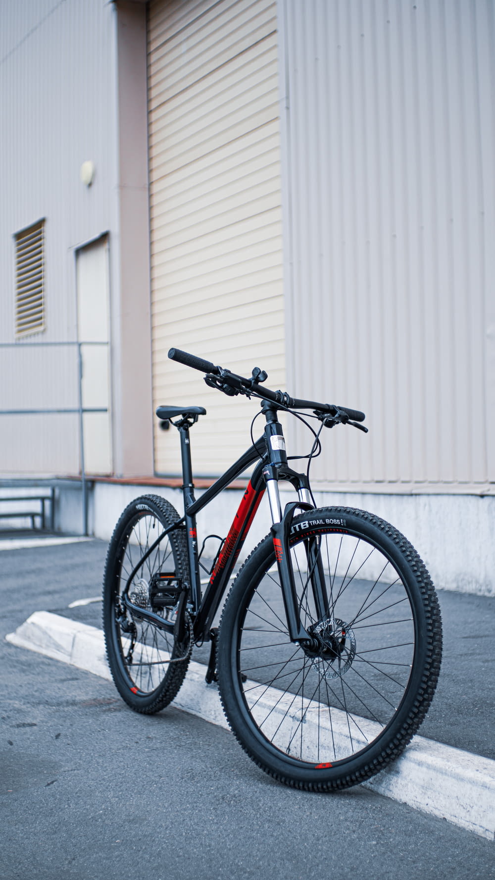 검은 색과 주황색 도로 자전거가 흰 벽 옆에 주차