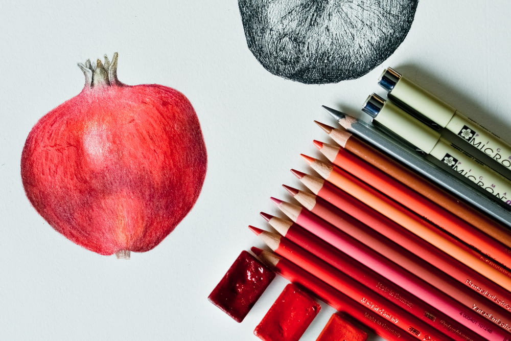 pomme rouge à côté d’un stylo noir et blanc