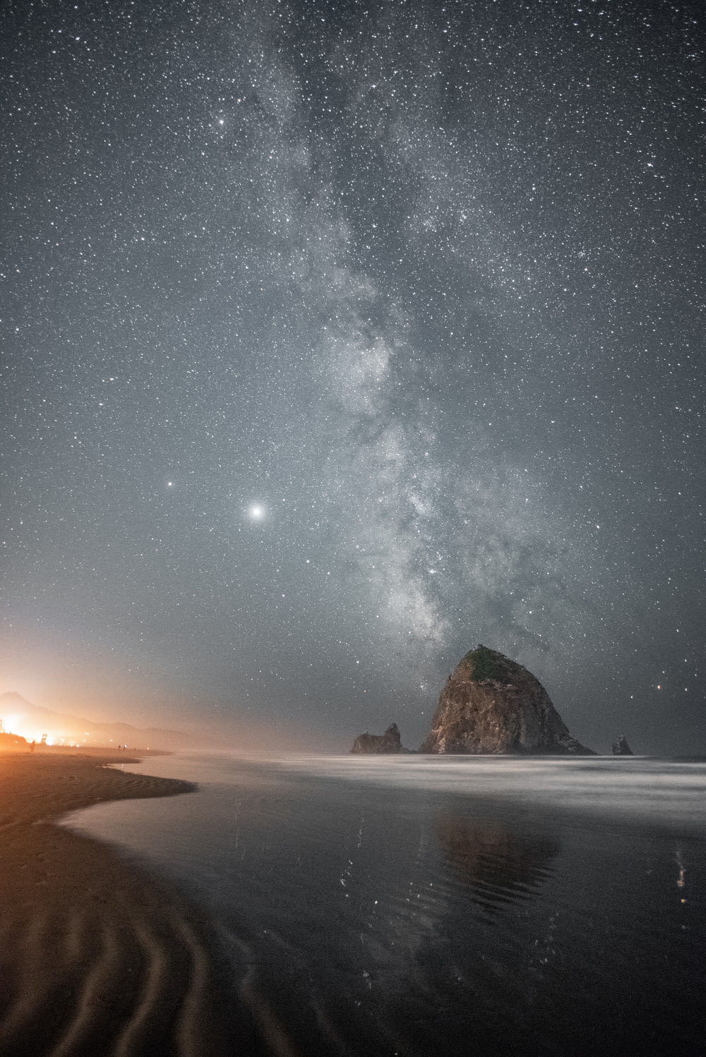 brown rock formation on sea shore under starry night