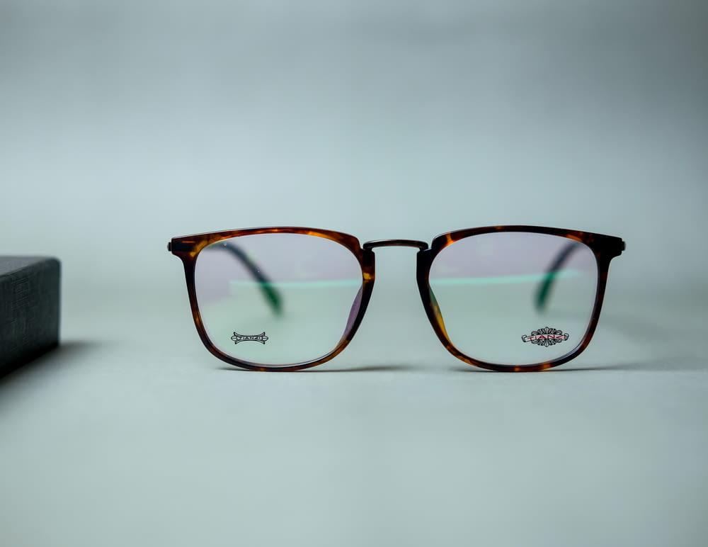 brown framed eyeglasses on white surface