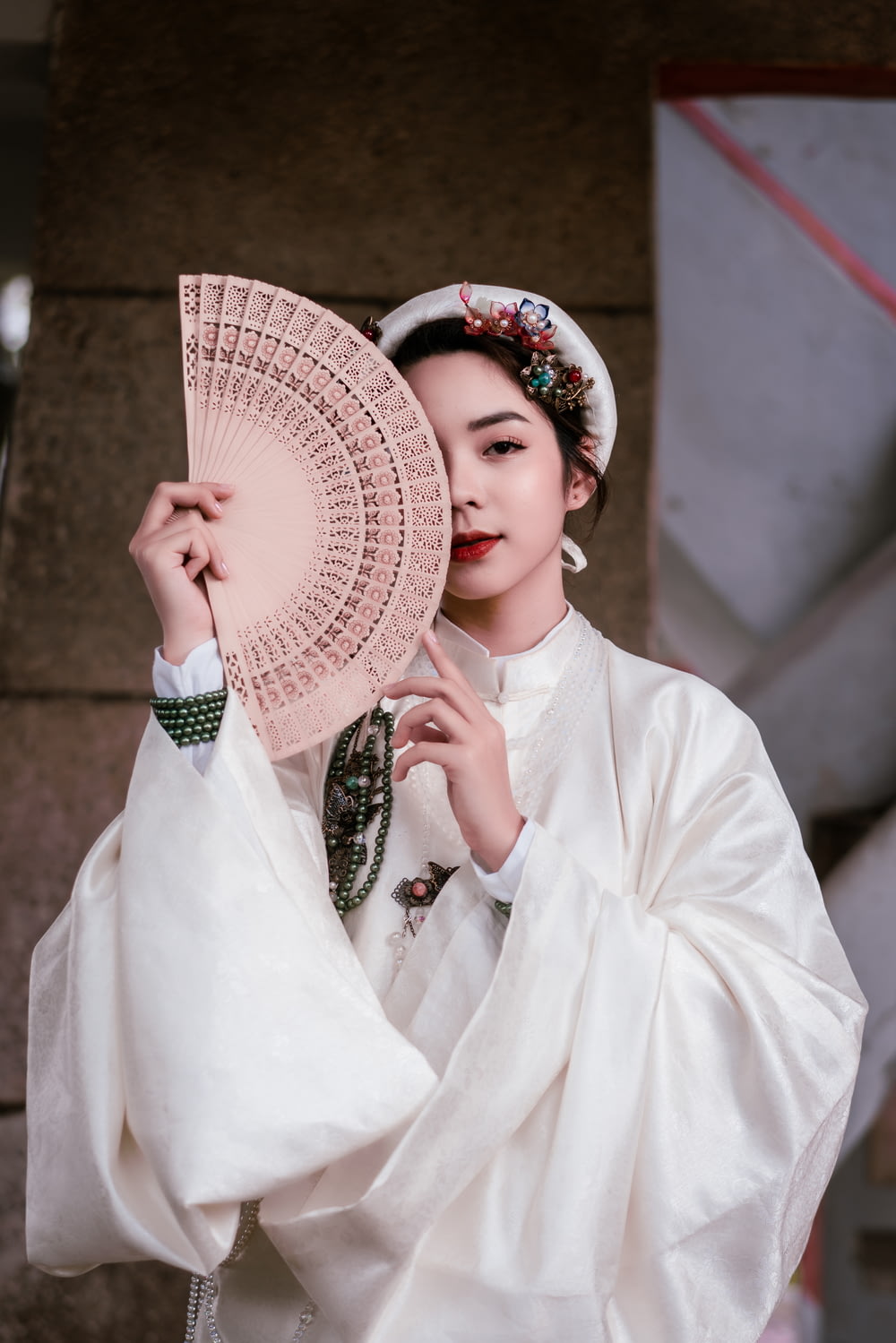 woman in white long sleeve shirt holding white hand fan
