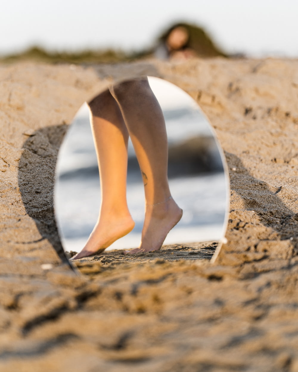 Donna in pompe di pelle bianca in piedi sulla sabbia marrone durante il giorno