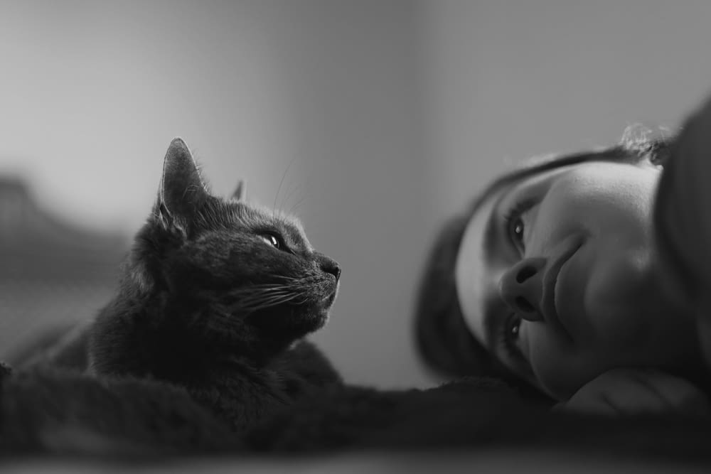 grayscale photo of cat on womans chest
