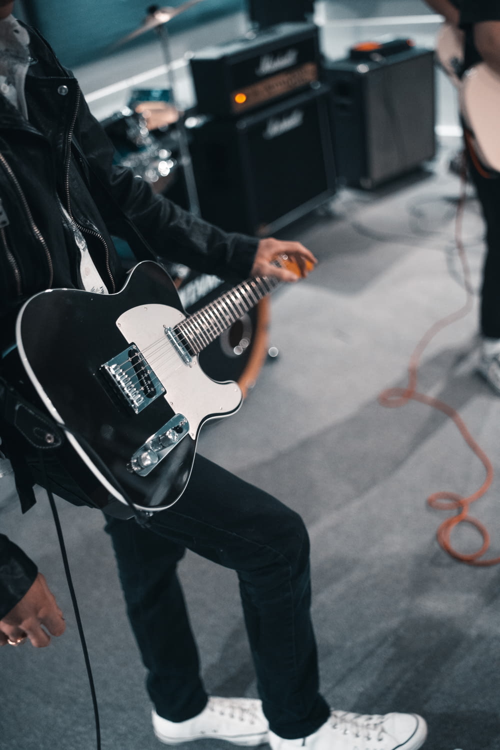 man in black jacket playing white electric guitar