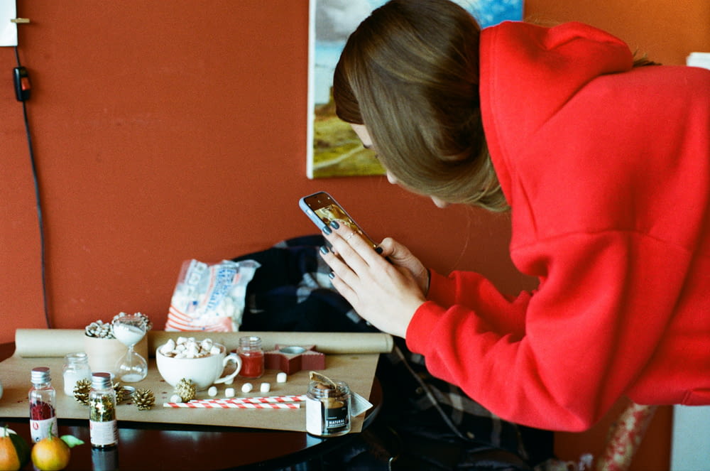 woman in red hoodie using smartphone