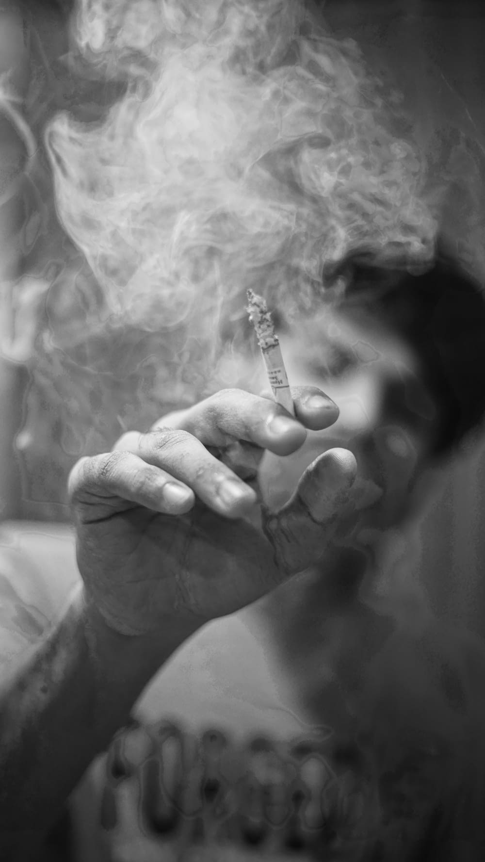 タバコのスティックを持っている人のグレースケール写真