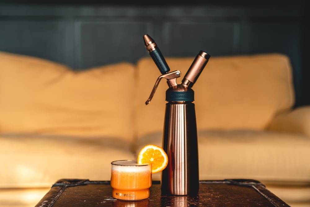Vaporizador tipo tubo negro y plateado junto a la vela naranja