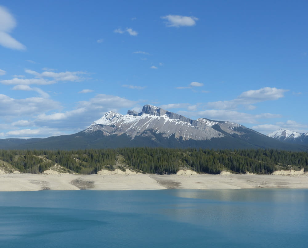snow covered mountain near lake under blue sky during daytime