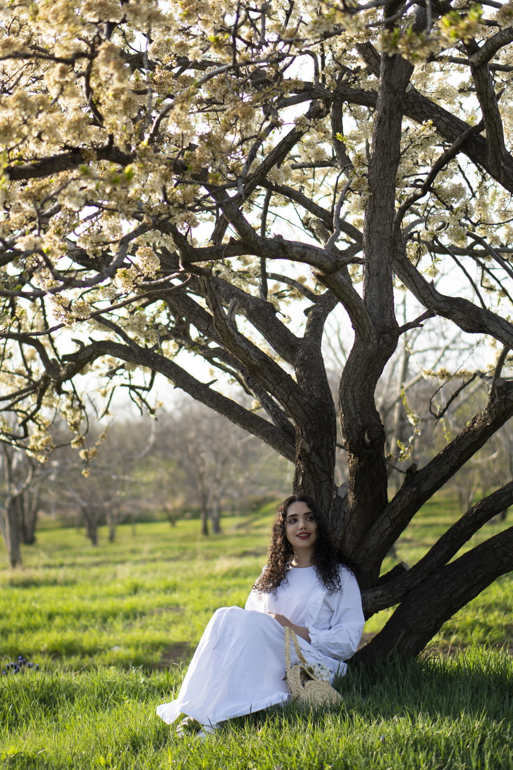 woman in white long sleeve shirt standing under brown tree during daytime