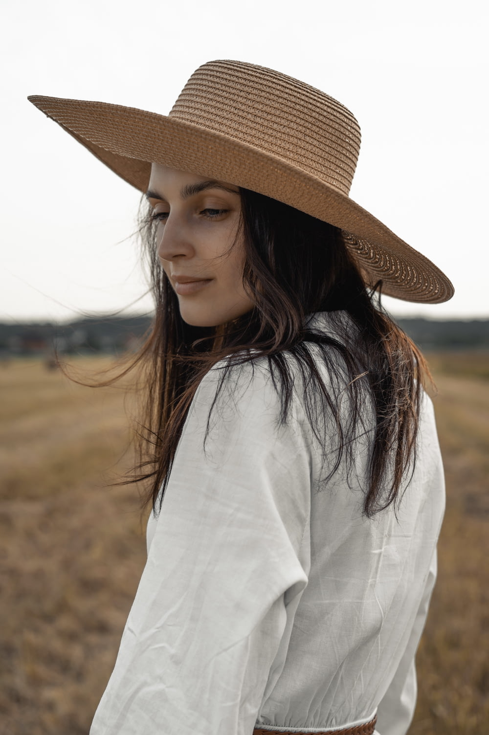 woman in white long sleeve shirt wearing brown straw hat