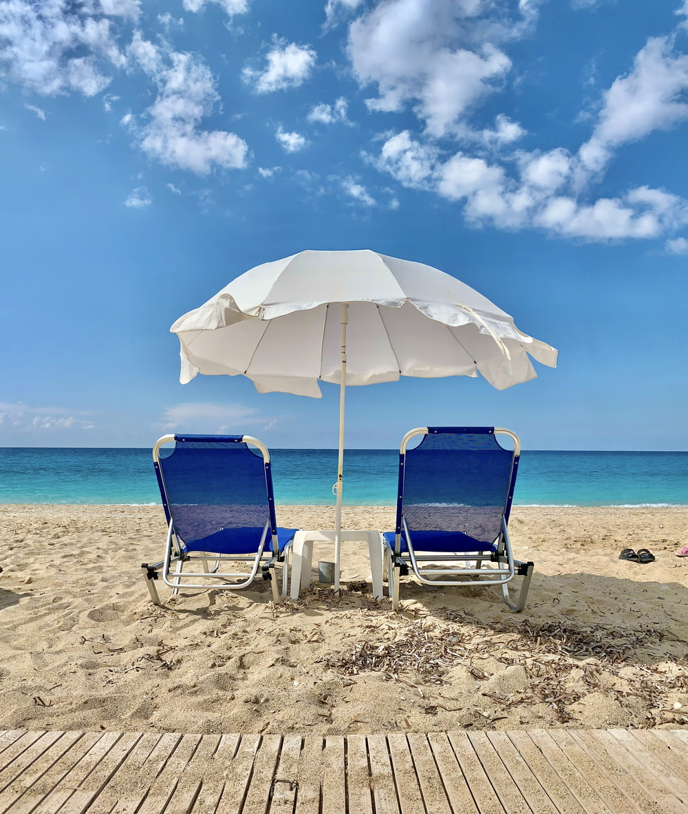 blue and white chair under white umbrella on beach during daytime