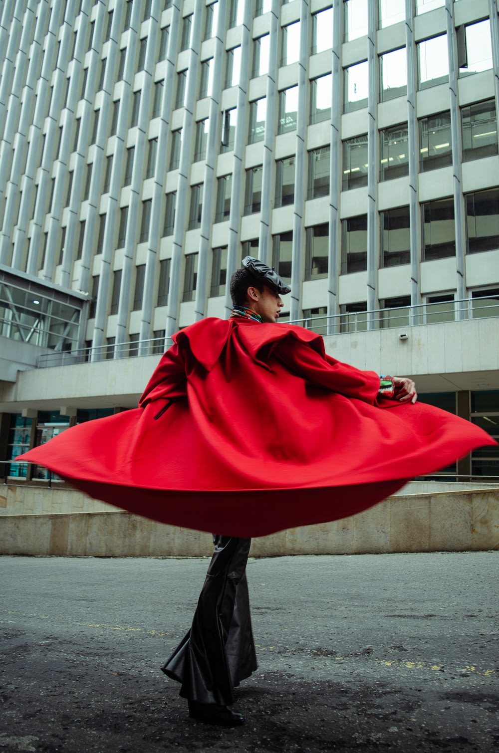 donna in cappotto rosso in piedi sul marciapiede durante il giorno