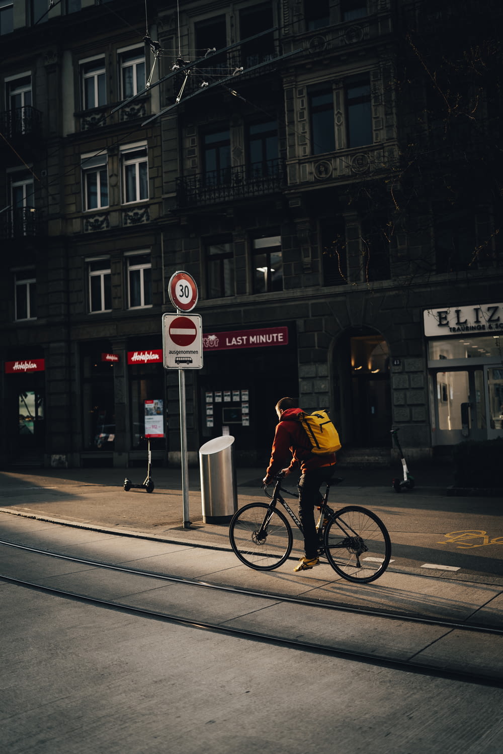 man in yellow jacket riding bicycle on road during daytime