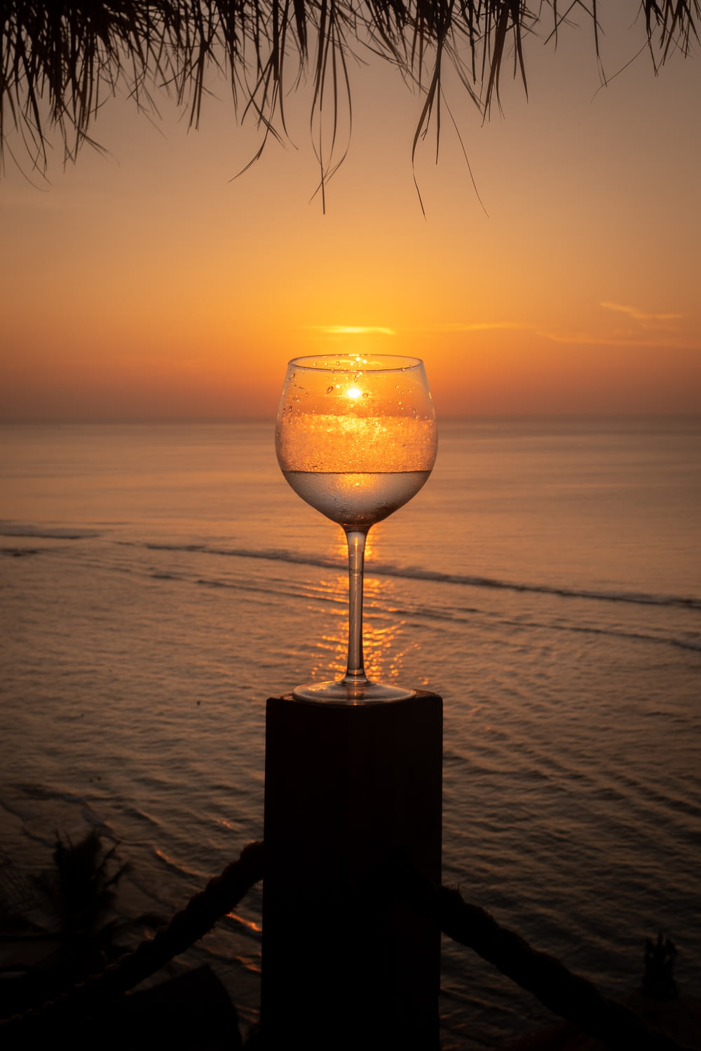 taça de vinho transparente na mesa de madeira marrom durante o pôr do sol