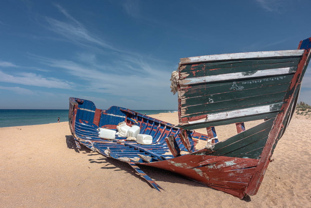 blue and red boat on beach during daytime
