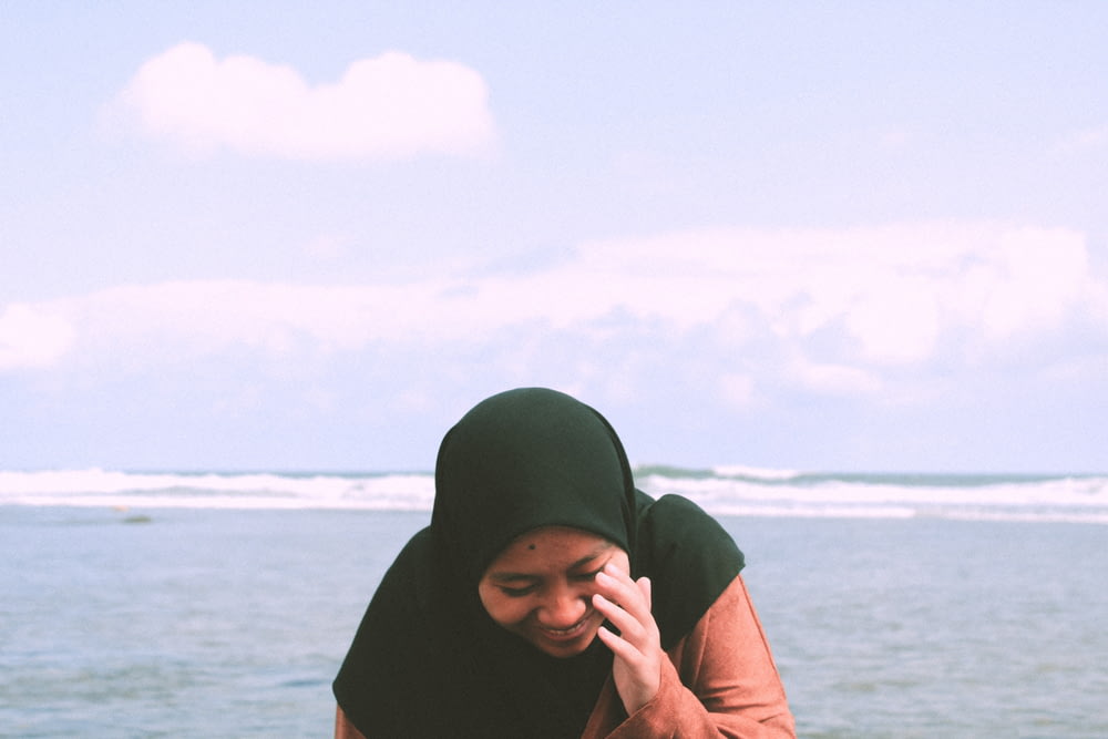 woman in black hijab near body of water during daytime