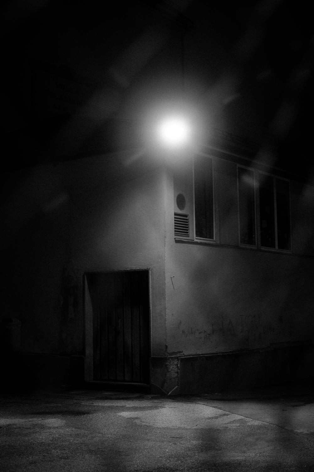 Foto in scala di grigi della lampadina accesa vicino alla finestra
