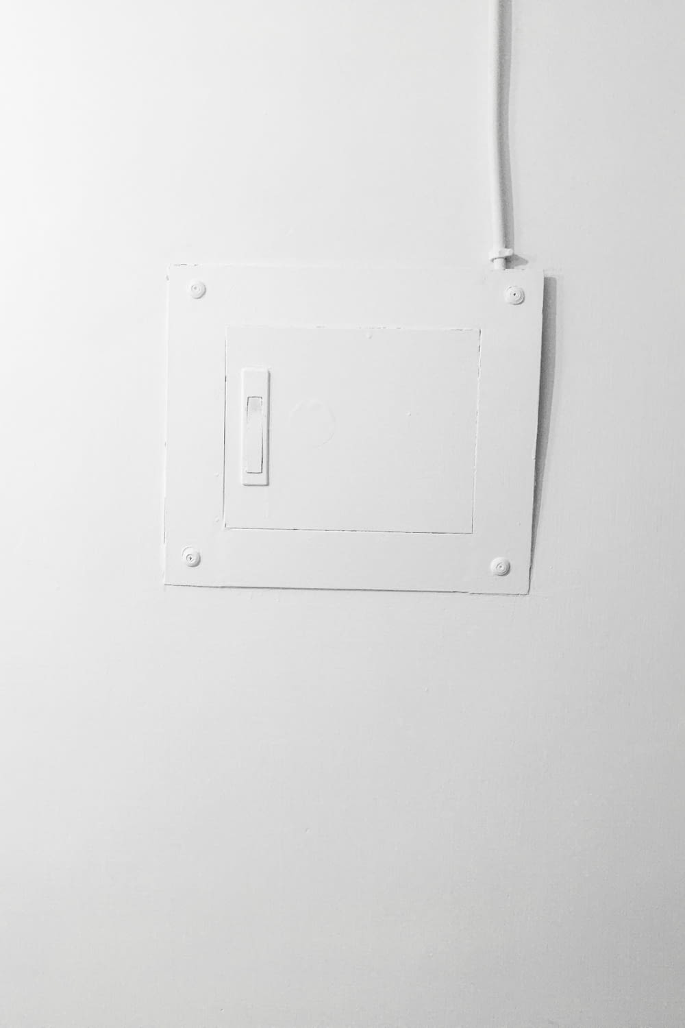 白く塗られた壁に取り付けられた白い電気スイッチ