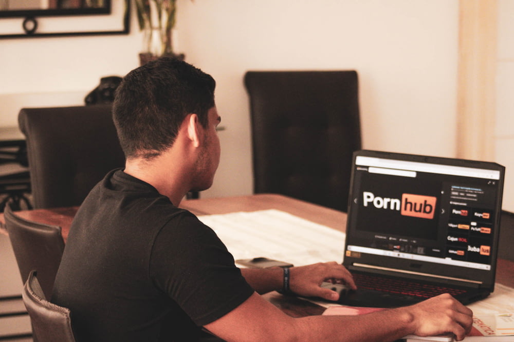 hombre en camiseta negra usando computadora portátil negra