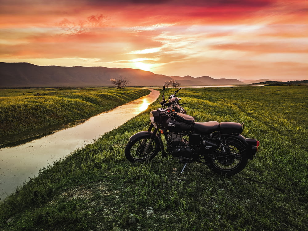 motocicleta negra en el campo de hierba verde durante la puesta del sol
