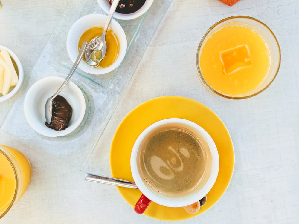 caneca de cerâmica branca com café no pires amarelo