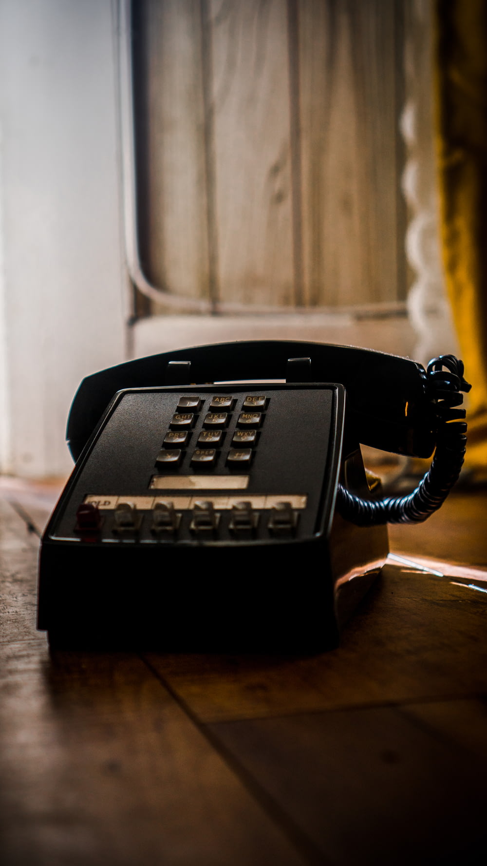 Teléfono negro sobre mesa de madera marrón